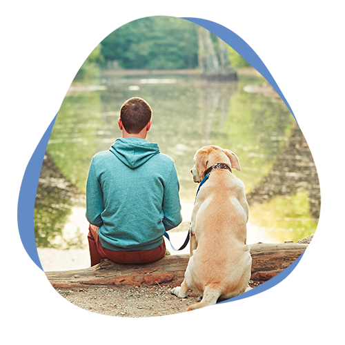 Ein Mann sitzt mit seinem Hund am See