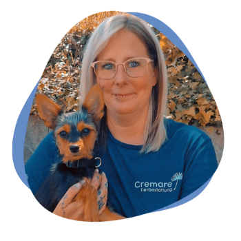 Junge Frau mit blonden Haaren und einem kleinen Hund auf dem Arm