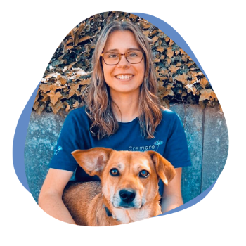 Junge Frau mit hellen Haaren, einer Brille und einem Hund im Arm