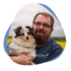 Mann mit Bart und Hund auf dem Arm