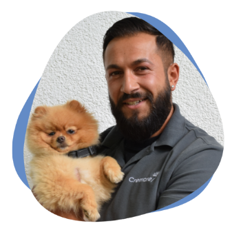 Junger Mann mit Bart und kleinem Hund auf dem Arm